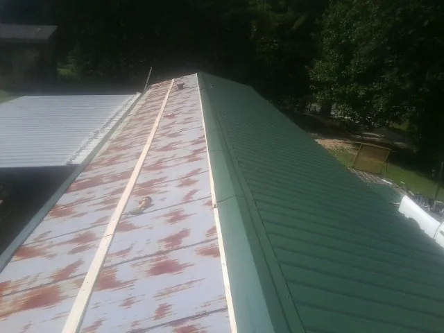 Old rusted panels beside newly installed green metal roofing — Wind Damage Roof Repair by Roofing Brothers in Hilliards