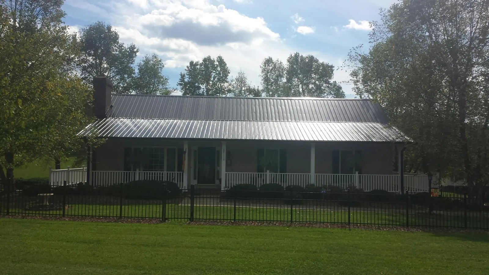 Gray metal roof on a brick ranch with a full width front porch — Gutter Guard Installation work by our crew in Hilliards