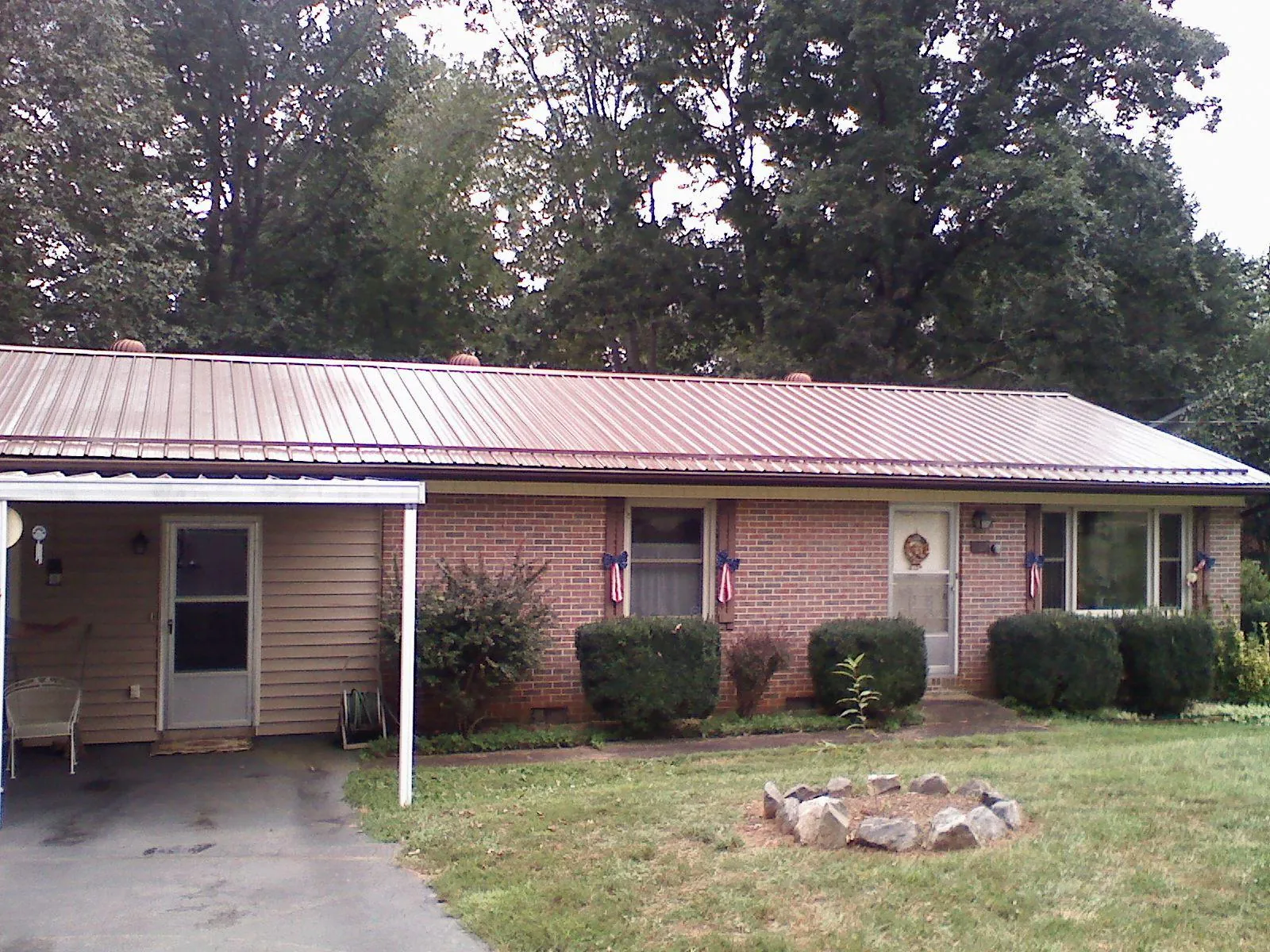 Bronze metal roof and carport on a brick ranch home — Roof Repair work by our crew in Hilliards