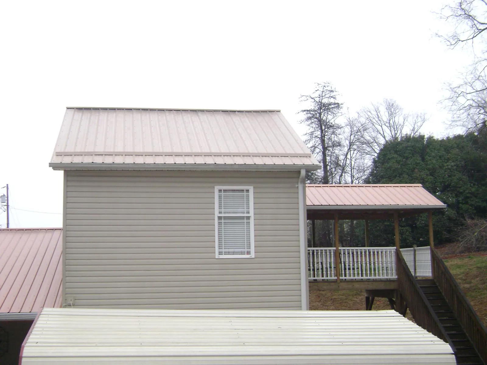 Tan metal roofs on a two story addition and attached porch, from a Roof Replacement job in Hilliards