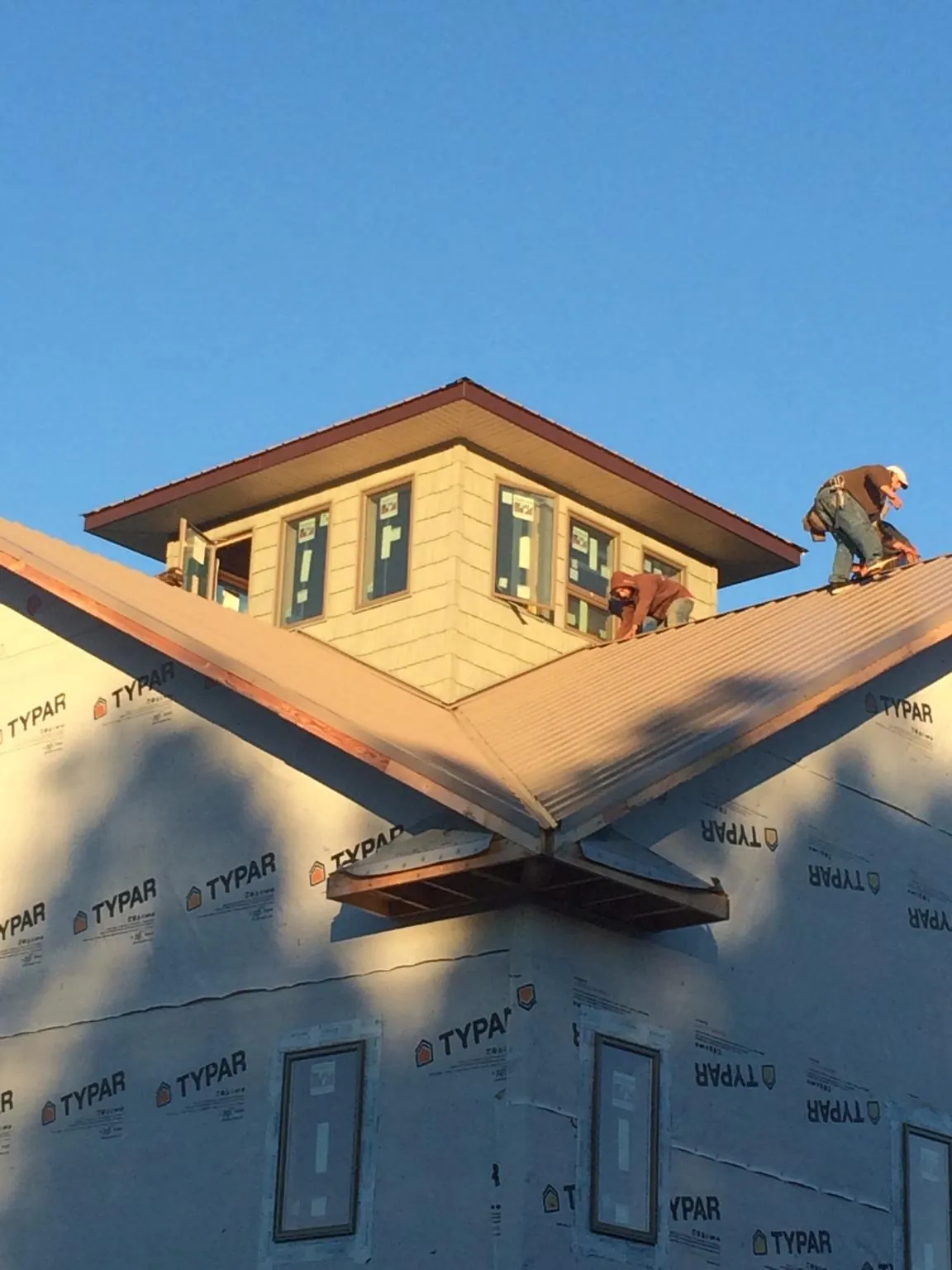 Roofers working around a rooftop cupola on a new metal roof at sunset — Roof Waterproofing in Hilliards by Roofing Brothers